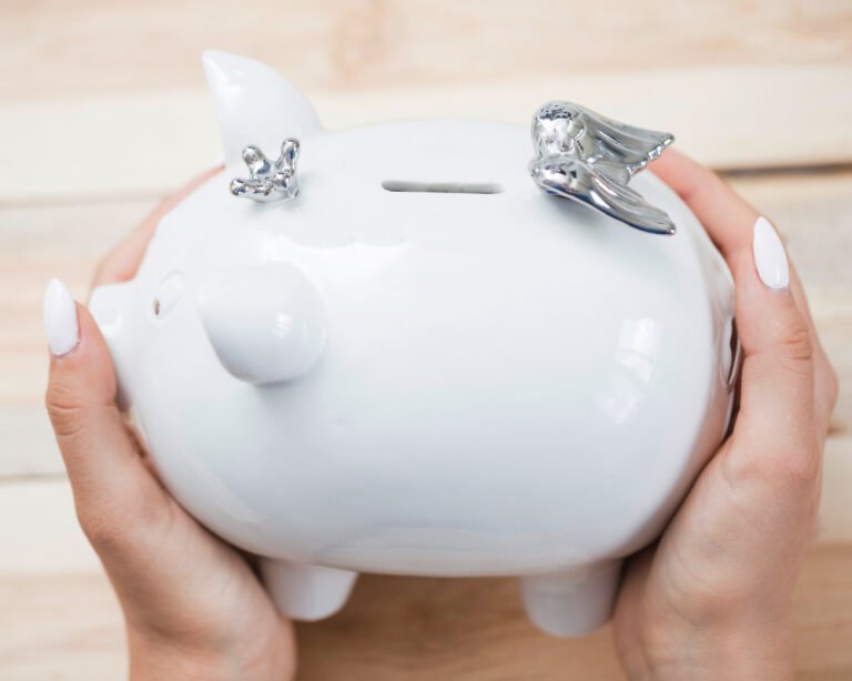 Woman's hands holding a piggy bank savings for wedding. She is calculating how much a wedding DJ cost in the UK.